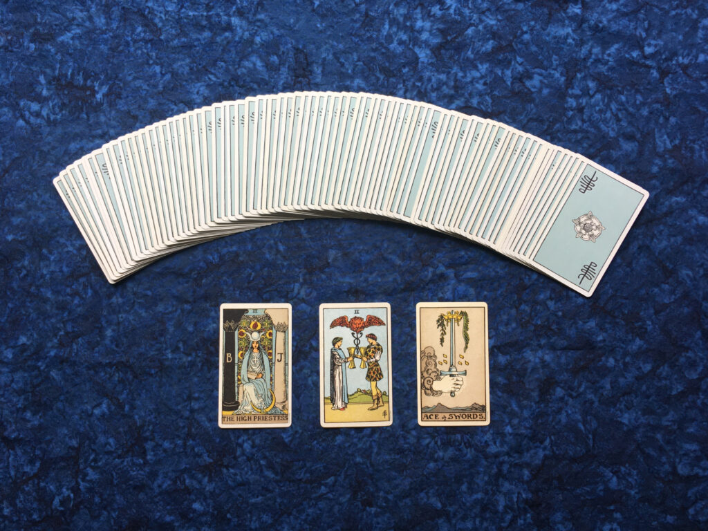 Baraja de tarot Rider-Waite desplegada con tres cartas boca arriba, entre ellas dos arcanos menores