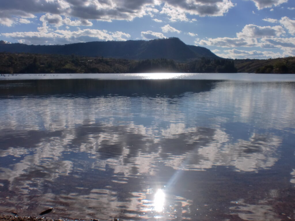 Paisaje con cielo, montaña, agua y reflejo del sol que evoca los cuatro elementos